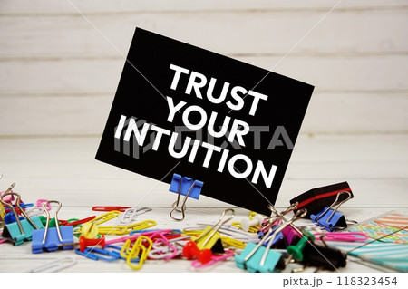 Trust Your Intuition text on paper card with stationary on wooden background 118323454