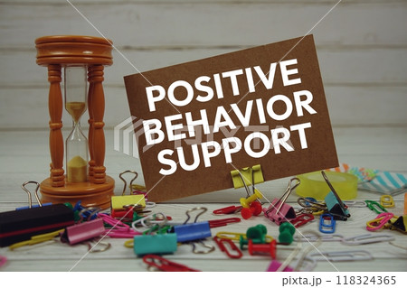Positive Behavior Support text on paper card with hourglass and stationary on wooden background Positive Behavior Support text on paper card with hourglass and stationary on wooden background 118324365