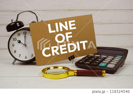 Line Of Credit text on paper card with alarm clock, calculator and magnifying glass on wooden background Line Of Credit text on paper card with alarm clock, calculator and magnifying glass on wooden background 118324540