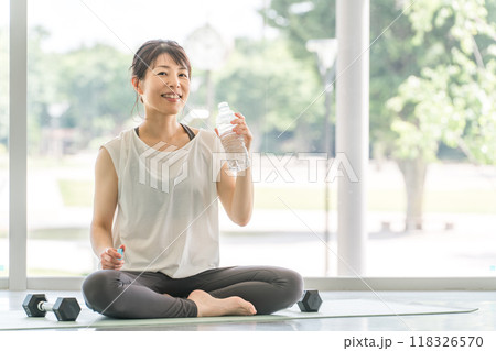 トレーニング後に水分補給するスポーツウェア姿の女性 118326570