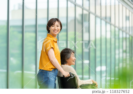 車椅子のシニア女性と介護する若い女性 車椅子のシニア女性と介護する若い女性 118327652