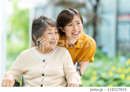 車椅子のシニア女性と介護する若い女性 車椅子のシニア女性と介護する若い女性 118327655