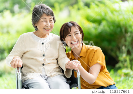 車椅子のシニア女性と介護する若い女性 車椅子のシニア女性と介護する若い女性 118327661