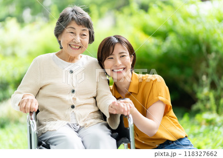 車椅子のシニア女性と介護する若い女性 車椅子のシニア女性と介護する若い女性 118327662