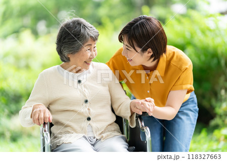 車椅子のシニア女性と介護する若い女性 車椅子のシニア女性と介護する若い女性 118327663