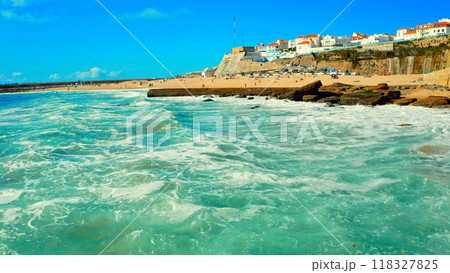 Beautiful resort touristic town on ocean background. Beautiful travel destination with sandy beach. Tourist beach for surfing while vacation at Ericeira, in Summer. Low angle view. Rocky coastline. Beautiful resort touristic town on ocean background. Beautiful travel destination with sandy beach. Tourist beach for surfing while vacation at Ericeira, in Summer. Low angle view. Rocky coastline. 118327825