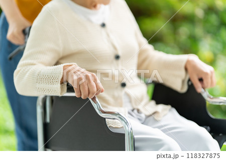 車椅子のシニア女性と介護する若い女性 手元 車椅子のシニア女性と介護する若い女性 手元 118327875