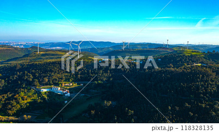 Wind farm generating green energy. Wind turbines with blades in field aerial view. Alternative energy. Scenic Aerial view of wind turbines farm over green beautiful landscape. Wind farm generating green energy. Wind turbines with blades in field aerial view. Alternative energy. Scenic Aerial view of wind turbines farm over green beautiful landscape. 118328135