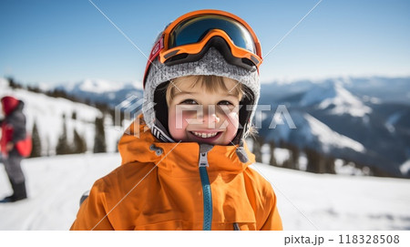 A happy kid standing on a ski slope at a ski resort. A young smiling child in a skiing helmet and goggles standing on top of a snowy mountain on a sunny winter day. Kid skiing on winter holidays. 118328508