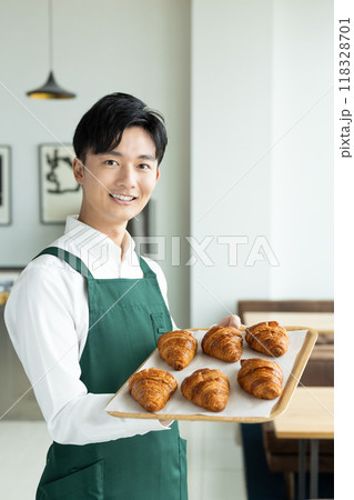 お客様に焼き立てパンをすすめる若い男性の店員 お客様に焼き立てパンをすすめる若い男性の店員 118328701