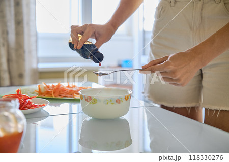 Preparing a flavorful dish by adding oyster sauce to a bowl in a bright kitchen setting Preparing a flavorful dish by adding oyster sauce to a bowl in a bright kitchen setting 118330276