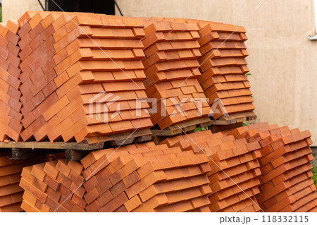 Stacks of new, red ceramic brick stacked on wooden pallets. 118332115