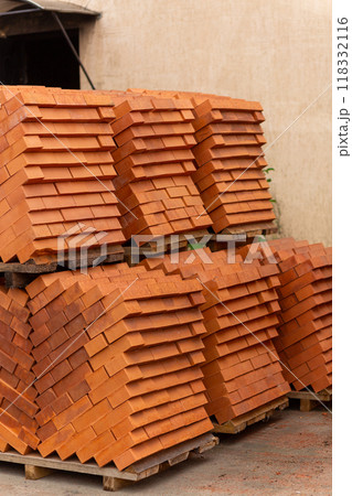 Stacks of new, red ceramic brick stacked on wooden pallets. 118332116