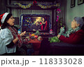 Christmas Kindness in Action: Social Worker and Senior Citizen Bond Over Holiday Tunes in Warmly Decorated Living Room. 118333028