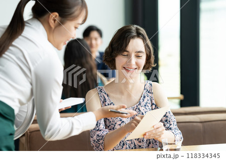 外国人観光客の接客をする若い女性の店員 118334345