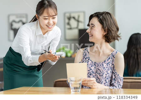 外国人観光客の接客をする若い女性の店員 118334349