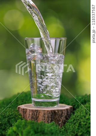 water pouring into glass on stump with moss 118337587