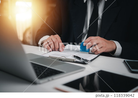 Businessman in suit stamping a document, approving contract. Professional corporate setup for legal agreements, official paperwork. Signature, authority process. 118339042