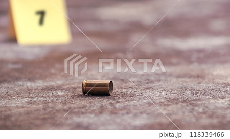 Spent bullet casing lying on the ground with blur number 9 sign. Concepts of shooting sports and security highlighting the dual nature of firearms in both competitive sport and protective measures. 118339466