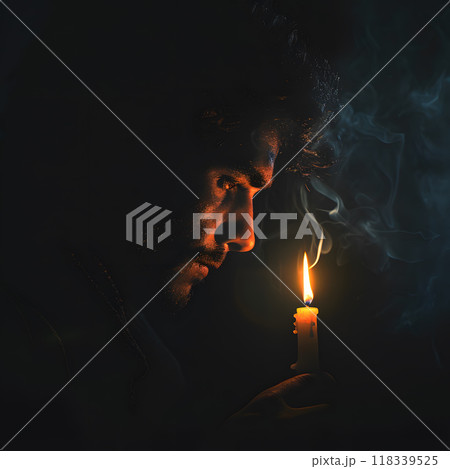 Man gazes intently at flickering candle, deep in thought as soft light illuminates his face. Atmosphere feels calm and introspective. 118339525