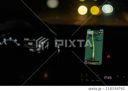 A person is driving in the dark, relying on a navigation app on their smartphone to guide them along the road. A person is driving in the dark, relying on a navigation app on their smartphone to guide them along the road. 118339742