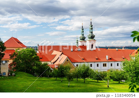 Historic red roof monastery building with garden full of green trees and lawn 118340054