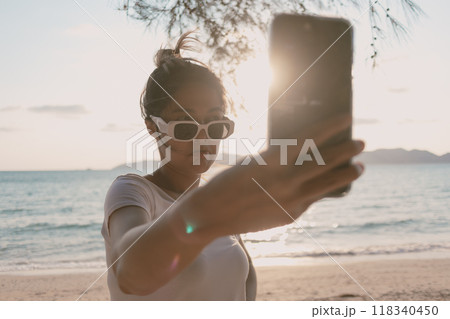 Woman is taking selfie photo of herself at the beach. 118340450