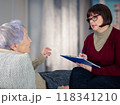 Professional in maroon sweater listens intently as senior client discusses estate plans in comfortable domestic setting. 118341210