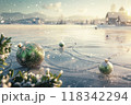 Snow-Covered Frozen Lake at Sunset with Christmas Decorations and a Distant Church in a Misty Mountain Valley 118342294