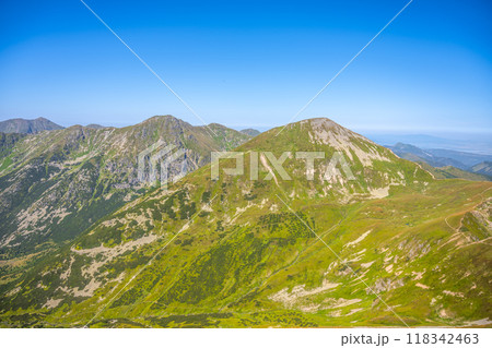 The picturesque landscape of the Western Tatras showcases lush green slopes under a clear blue sky, inviting hikers and nature lovers to explore its scenic beauty during summer. 118342463