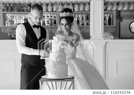 Elegant and Joyous Wedding Celebration Featuring a Bride and Groom Cutting Their Beautifully Decorated Cake in a Charming Venue Elegant and Joyous Wedding Celebration Featuring a Bride and Groom Cutting Their Beautifully Decorated Cake in a Charming Venue 118343376
