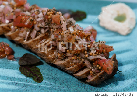 Exquisite Plated Gourmet Dish with Fresh Tomato and Herb Topping Presented on Elegant Blue Ceramic Plate 118343438