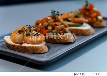 Gourmet Appetizer Platter with Assorted Bruschetta on Rustic Wooden Tray in Elegant Table Setting 118343439