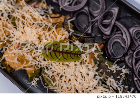 Freshly Shredded Cheese and Red Onion Garnished Savory Delicacy with Herb Leaf in Elegant Presentation on Dark Plate Freshly Shredded Cheese and Red Onion Garnished Savory Delicacy with Herb Leaf in Elegant Presentation on Dark Plate 118343470