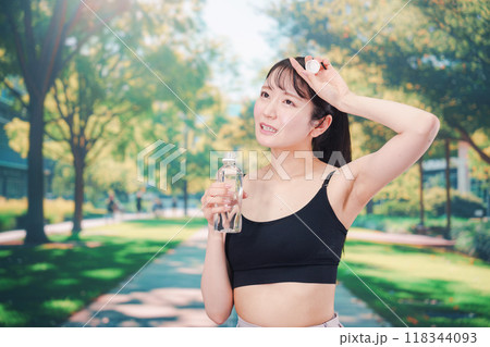 外でランニングをしながら水を飲む若い女性 118344093