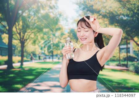 外でランニングをしながら水を飲む若い女性 外でランニングをしながら水を飲む若い女性 118344097