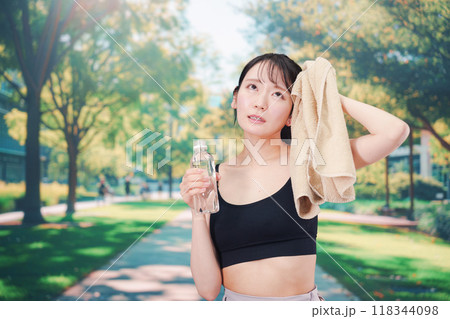 外でランニングをしながら水を飲む若い女性 外でランニングをしながら水を飲む若い女性 118344098