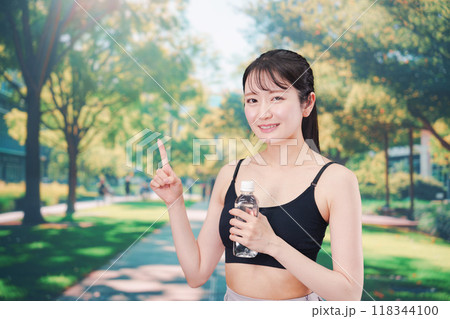 外でランニングをしながら水を飲む若い女性 118344100