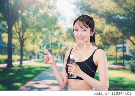 外でランニングをしながら水を飲む若い女性 外でランニングをしながら水を飲む若い女性 118344102
