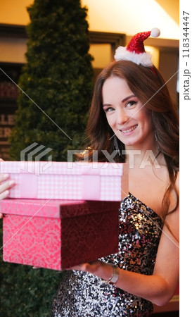 Girl holding Christmas present near New Year tree. Happiness emotions 118344447