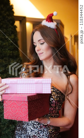 Girl holding Christmas present near New Year tree. Happiness emotions Girl holding Christmas present near New Year tree. Happiness emotions 118344452