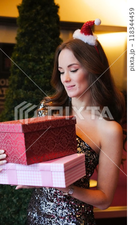 Girl holding Christmas present near New Year tree. Happiness emotions Girl holding Christmas present near New Year tree. Happiness emotions 118344459