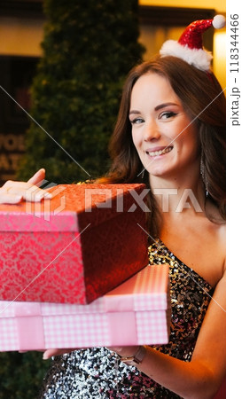 Girl holding Christmas present near New Year tree. Happiness emotions 118344466