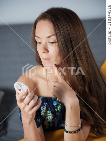 The girl looks into a small mirror The girl looks into a small mirror 118344516
