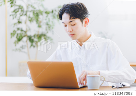 自宅でノートパソコンを使う若い男性 自宅でノートパソコンを使う若い男性 118347098