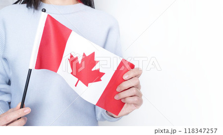 Unrecognized girl student in white blue shirt holding small Canadian flag over gray background, Canada day, holiday, vote, immigration, tax, copy space Unrecognized girl student in white blue shirt holding small Canadian flag over gray background, Canada day, holiday, vote, immigration, tax, copy space 118347257
