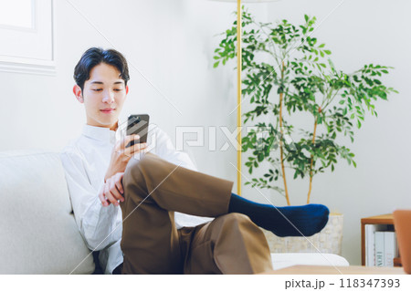 リビングでスマホを見る若い男性 リビングでスマホを見る若い男性 118347393