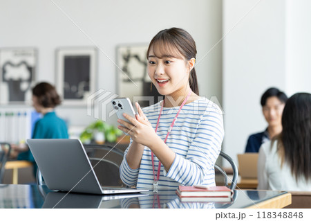 オフィスでスマホを操作する若い女性 オフィスでスマホを操作する若い女性 118348848
