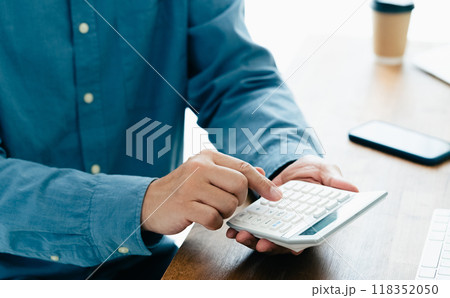 電卓で計算する男性の手元 118352050