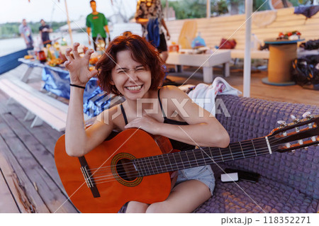 Funny young woman with guitar at picnic. Summer party on the beach. Funny young woman with guitar at picnic. Summer party on the beach. 118352271